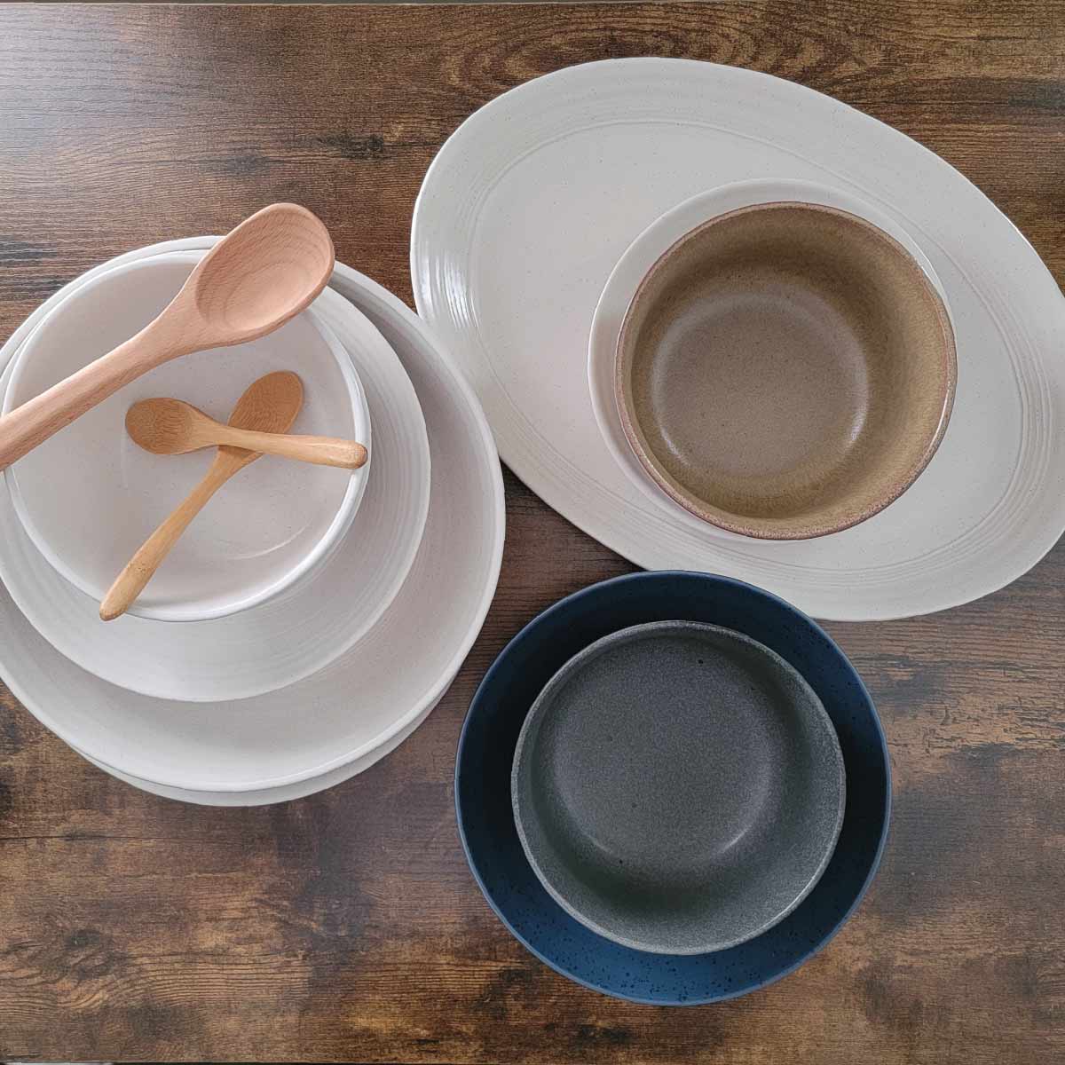 Bowls and plates of different sizes and colors along with small wooden spoons.