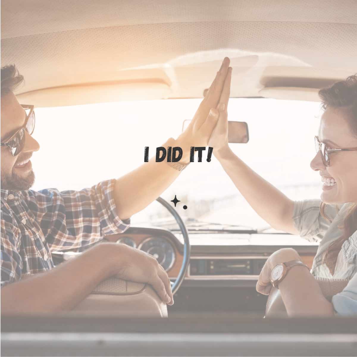 I did it! A man and a woman sitting in the front seats of a car giving each other a high five.