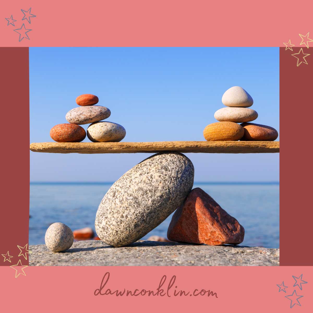 Stones being balanced like on a scale in front of a big body of water.